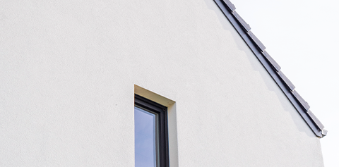 Façade moderne d’une maison Piron, alliant crépi blanc et aluminium noir